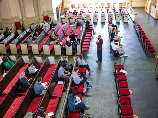 people seated in Hendricks Chapel with person standing in aisle