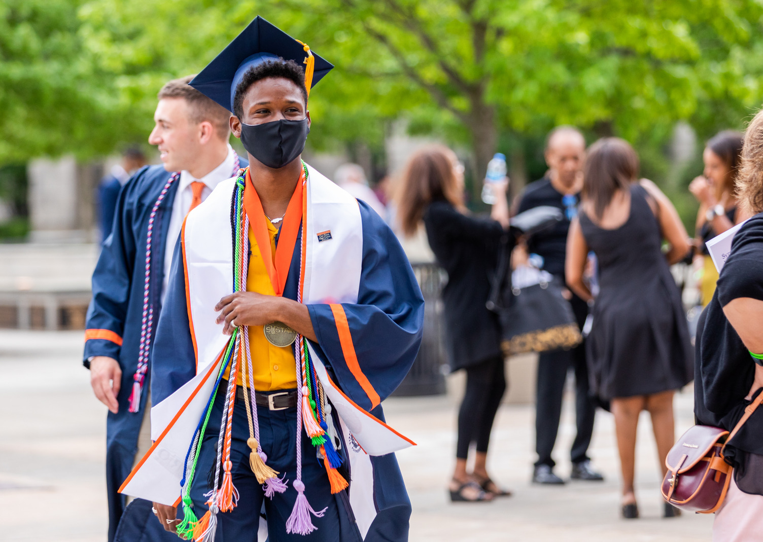 a student walks outdoors in cap and gown during Commencement weekend 2021