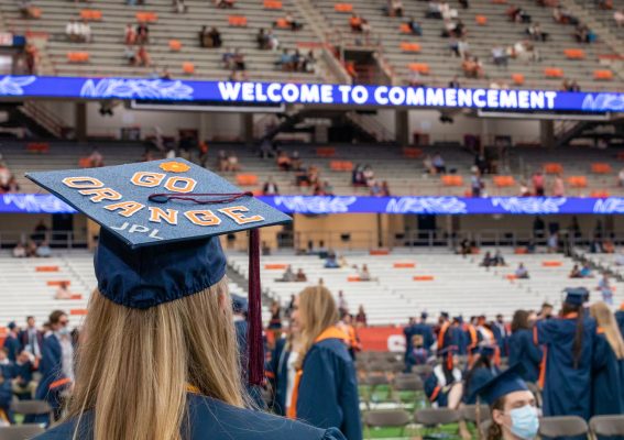 a graduate whose hat says GO ORANGE in the stadium for Commencement 2021