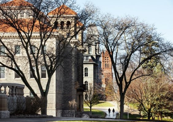 Two students walking across campus in early spring