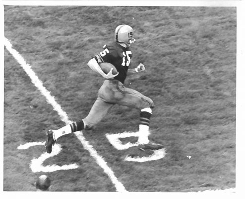 person in athletic uniform running with football