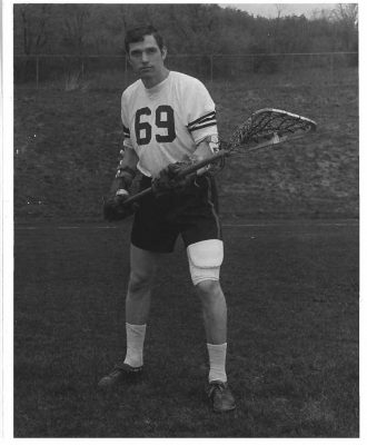 person in sports uniform holding lacrosse stick