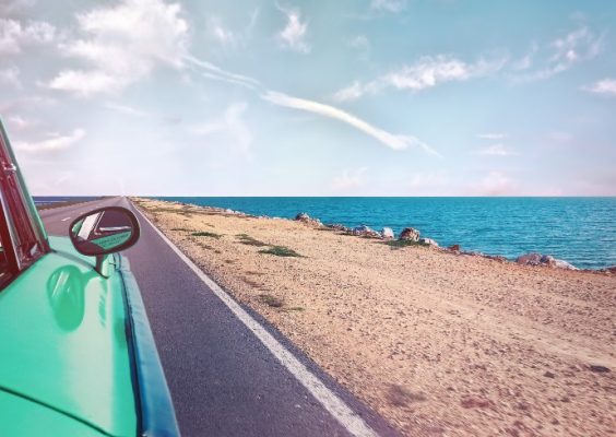 stock image of car driving on a road along a beach