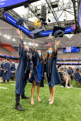 three graduates throwing their caps in the air during Commencement 2020