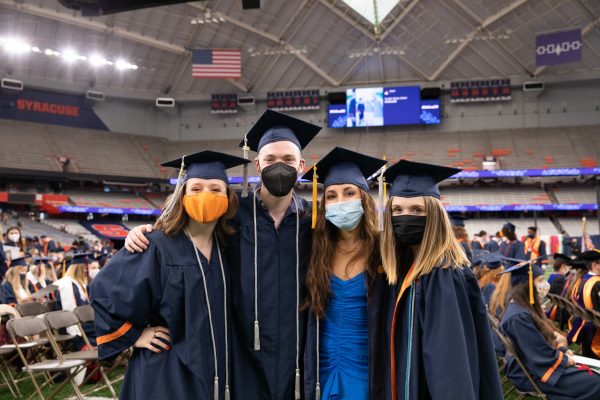 four people in caps and gowns at Commencement 2020 on Sept. 19, 2021, in the stadium