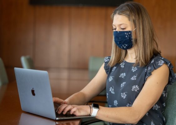 student using a laptop computer wearing a mask