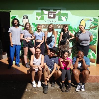 group of student interns pose in front of wall sign at the Costa Rica Animal Rescue