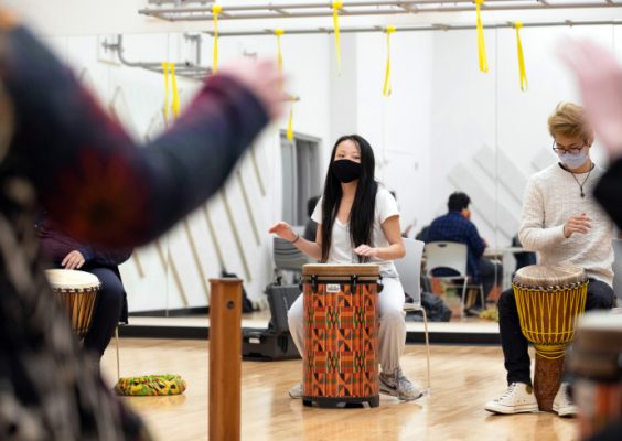 people seated playing hitting drums