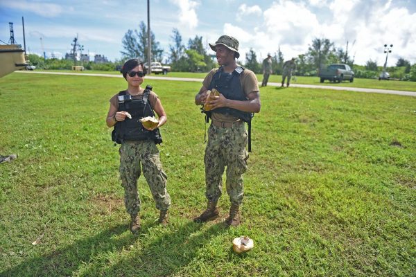 two people in military uniforms holding coconuts