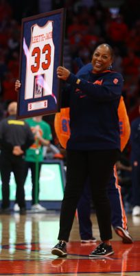person standing on basketball court in stadium holding a frame with a basketball shirt uniform