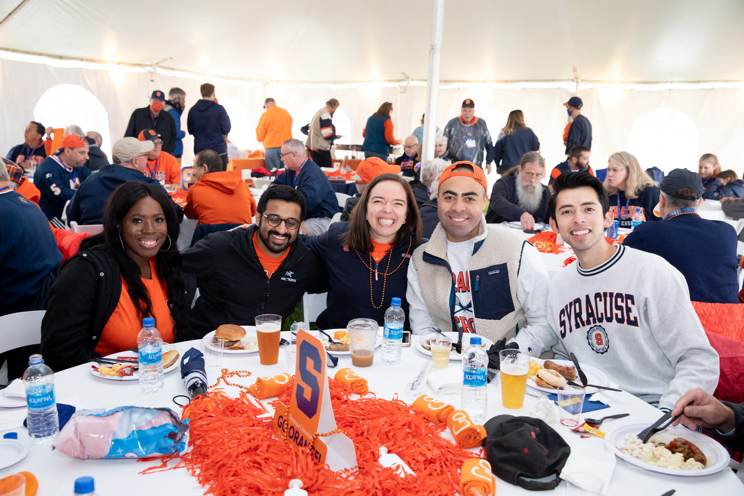 group of friends pose together during a meal at the Orange Central tailgate celebration