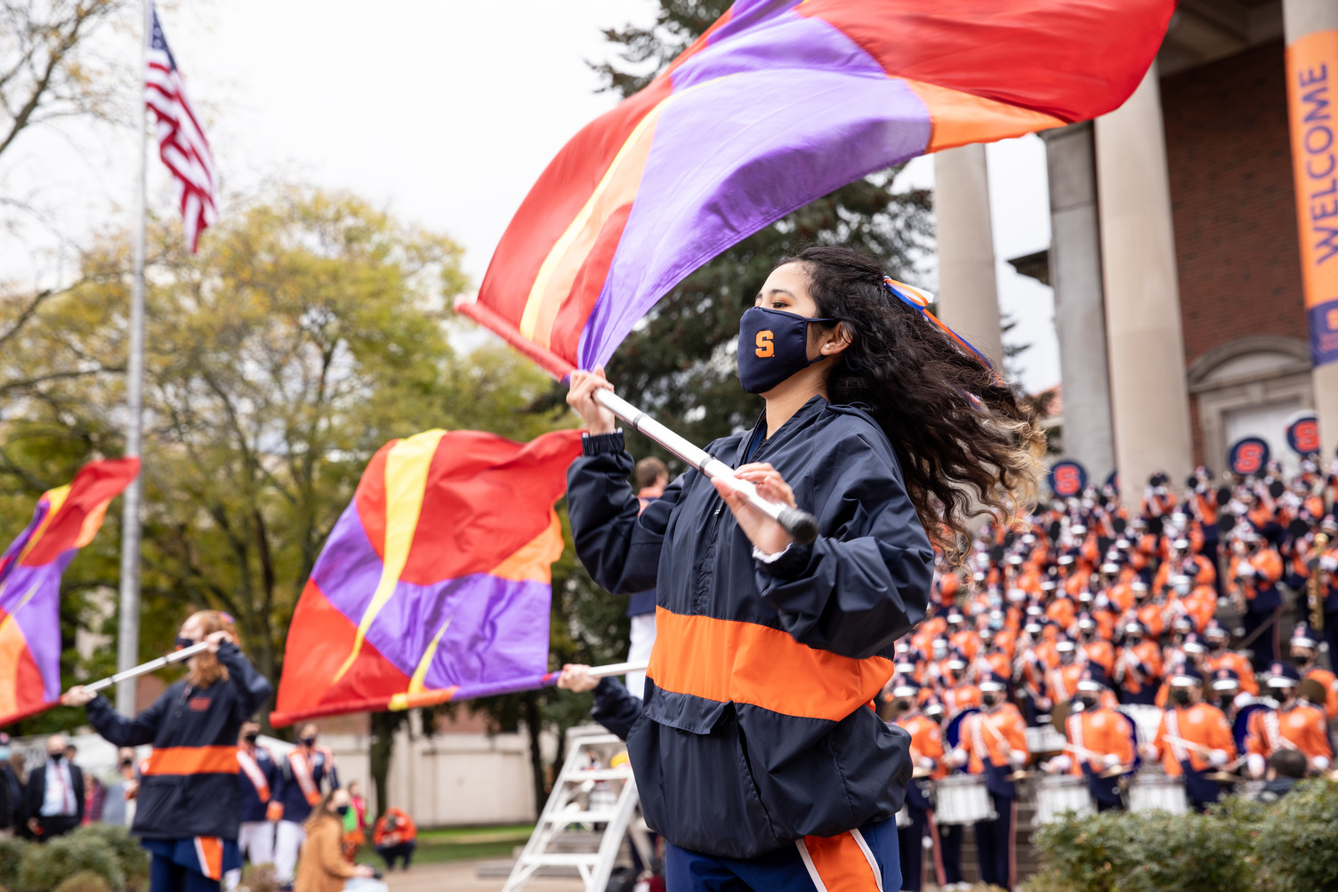 member of the flag corps waves a colorful flag during a marching band performance