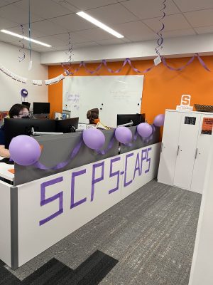 welcome desk with purple decorations and people seated behind desk