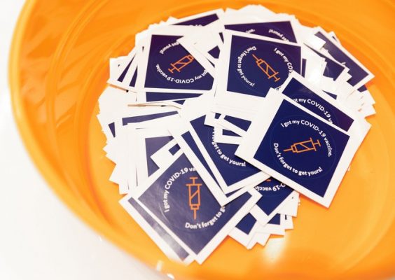 a bowl of stickers that say "I got my COVID-19 vaccine, Don't forget to get yours!"