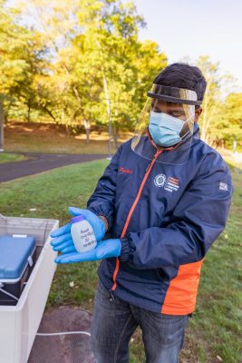 Pruthvi Kilaru holds up a wastewater sample from Syracuse's own wastewater surveillance program monitoring residence halls for the presence of COVID-19