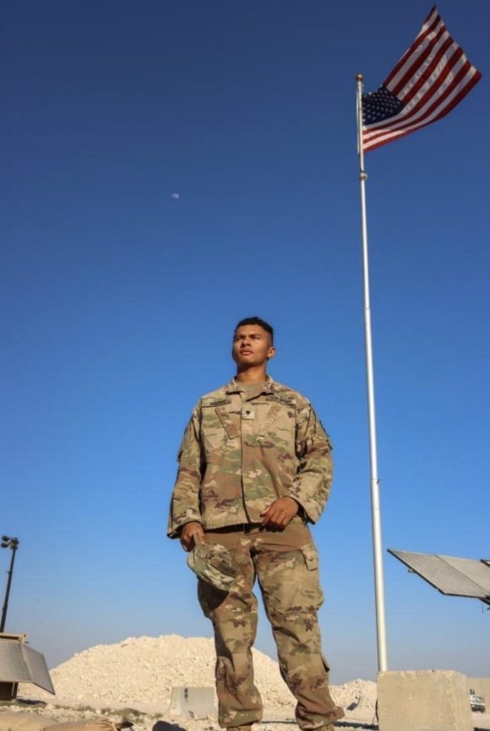 person in uniform standing in front of flag pole