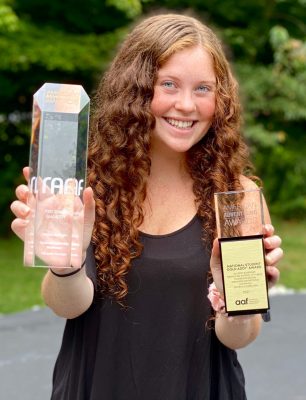 person outside holding two awards