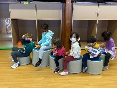 several children sitting on small stools in classroom