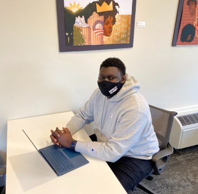 Mamoudou Camara sits at a table at 119 Euclid. working on a laptop