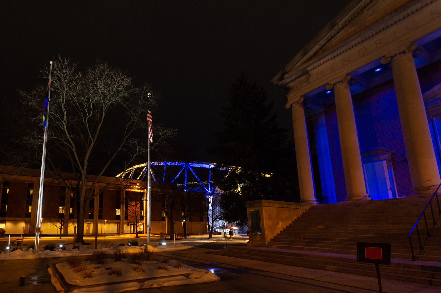 campus buildings at night lit up in blue and yellow