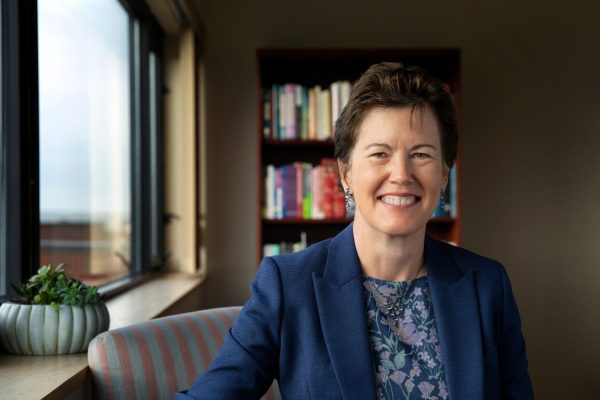 Environmental portrait of Provost Gretchen Ritter on a striped sofa in front of a bookcase