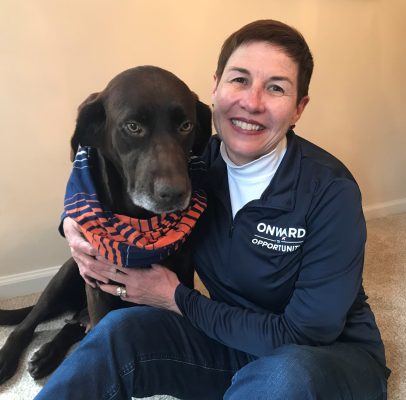 Paulina Thompson with a dog wearing a blue and orange scarf