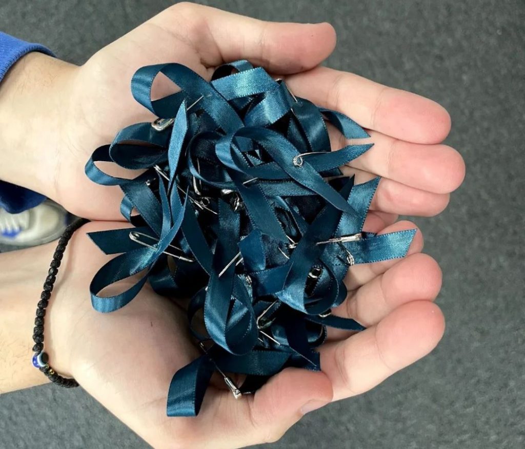 hands holding pile of teal ribbons