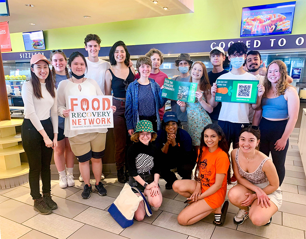 Μαθητές εθελοντές με το δίκτυο Food Recovery ποζάρουν και κρατούν πινακίδες στο Graham Dining Center