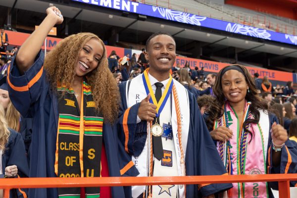 three people wearing graduation gowns in stadium