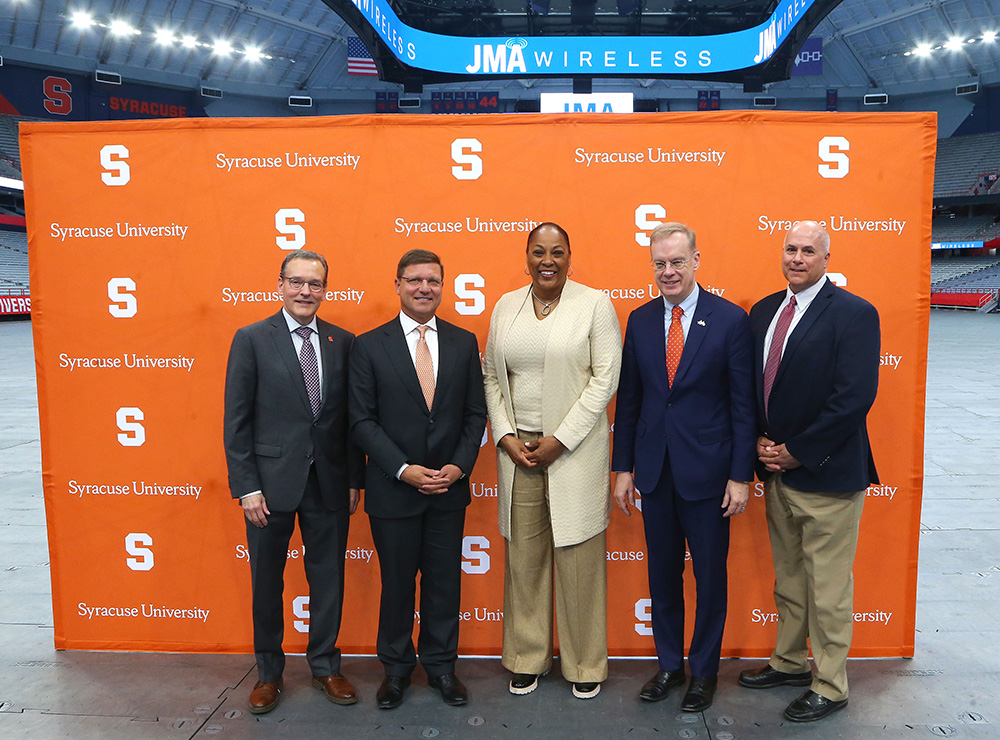 John Wildhack, John Mezzalingua, Felisha Legette-Jack, Chancellor Kent Syverud and Pete Sala stand in front of a Syracuse University step-and-repeat banner in the JMA Wireless Dome