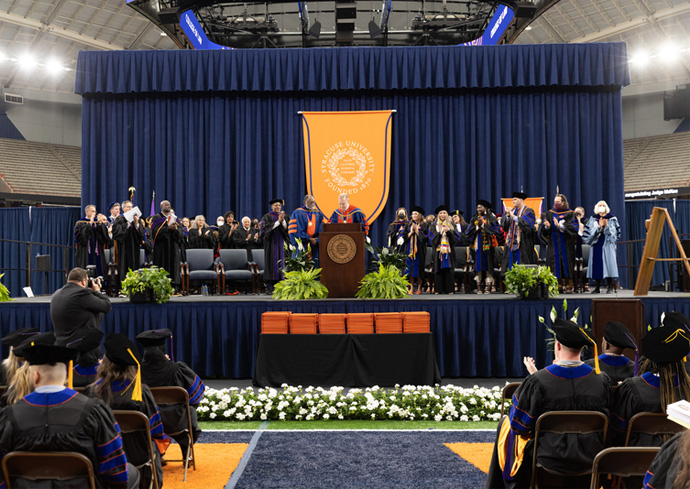 graduates, faculty and others on stage during the College of Law's 2022 Commencement
