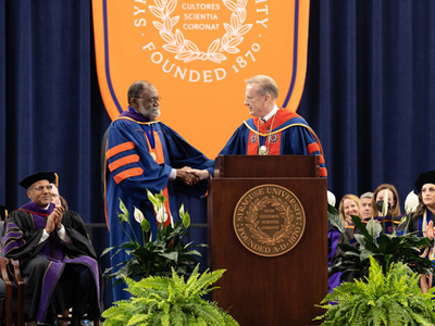 Chancellor Syverud shakes hands with Theodore A. McKee L’75 at the podium during the College of Law's 2022 Commencement ceremony