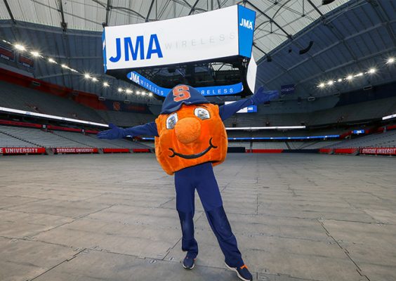 Otto stands in front of digital sign with JMA Wireless logo at the press event announcing the JMA Wireless Dome