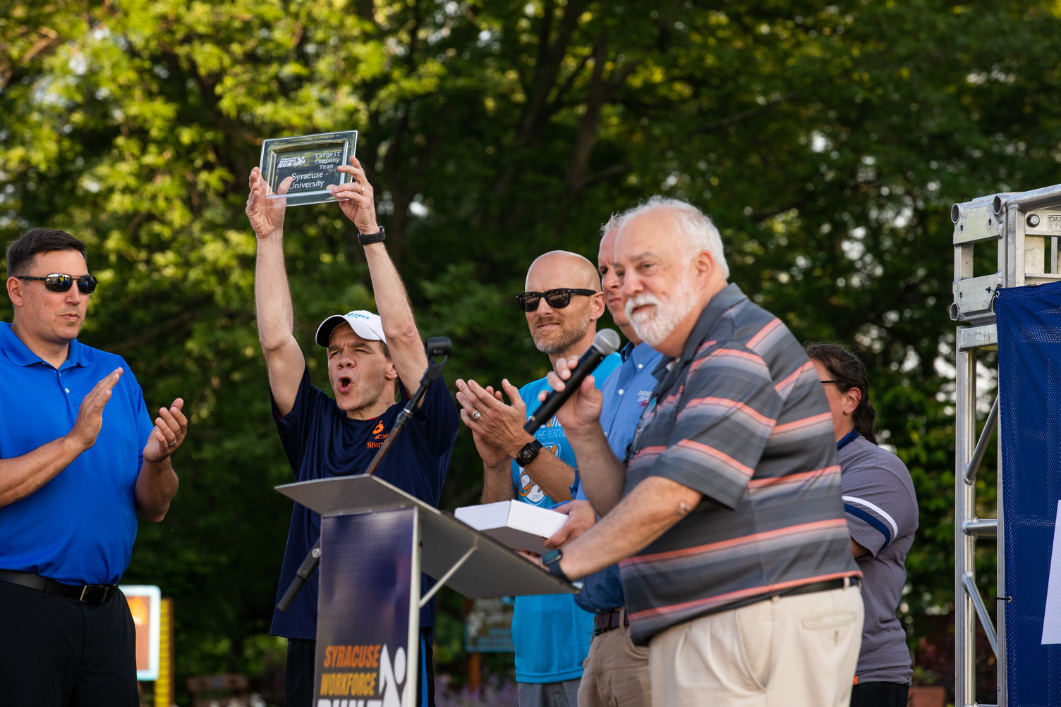 Dean of the College of Engineering and Computer Science J. Cole Smith holds up an award for the most participants recruited for the Syracuse Workforce Run