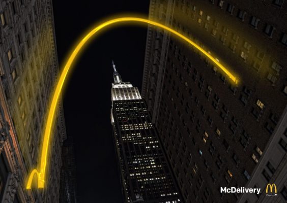 yellow arch rising over tall New York City building
