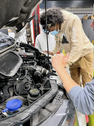 two people working on an automobile in the University's Automotive Garage
