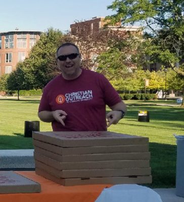 Baptist Chaplain Stoney Douthitt pointing to several boxes of pizza