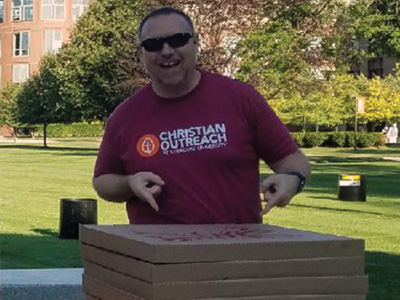 Baptist Chaplain Stoney Douthitt pointing to several boxes of pizza