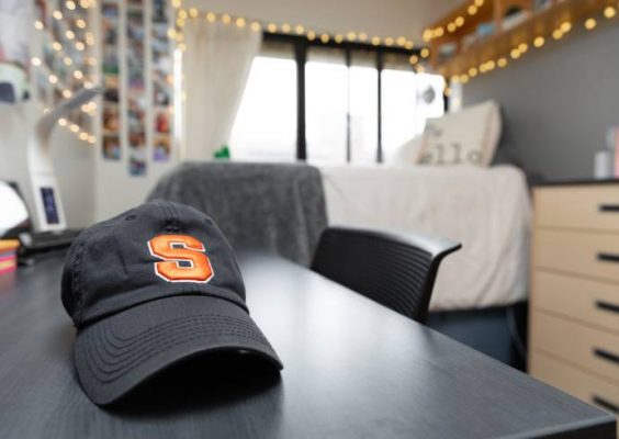 baseball cap with letter S on desk in residence hall room