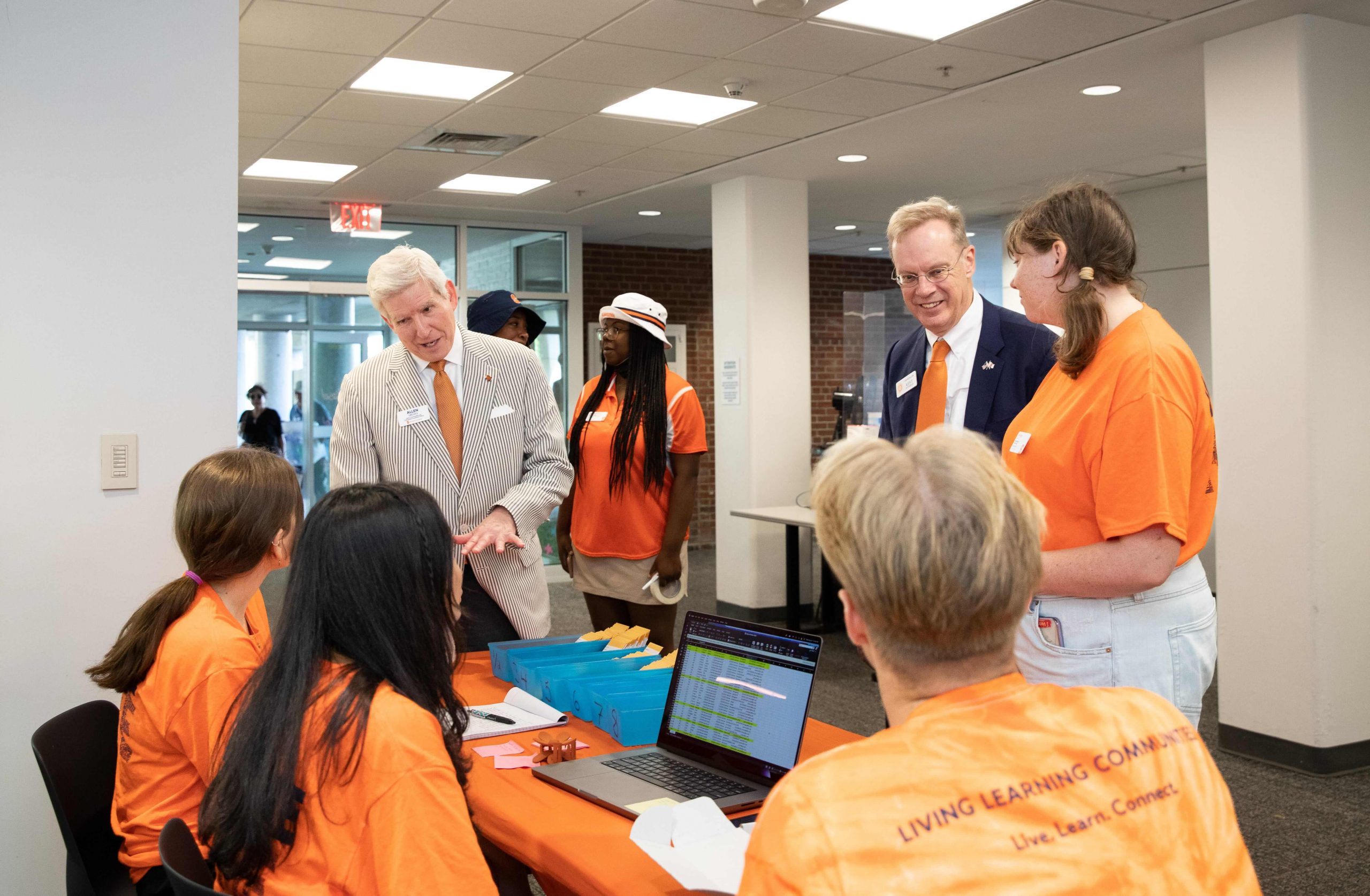 Allen Groves and Chancellor Kent Syverud visit with student volunteers at a check-in table during Syracuse Welcome