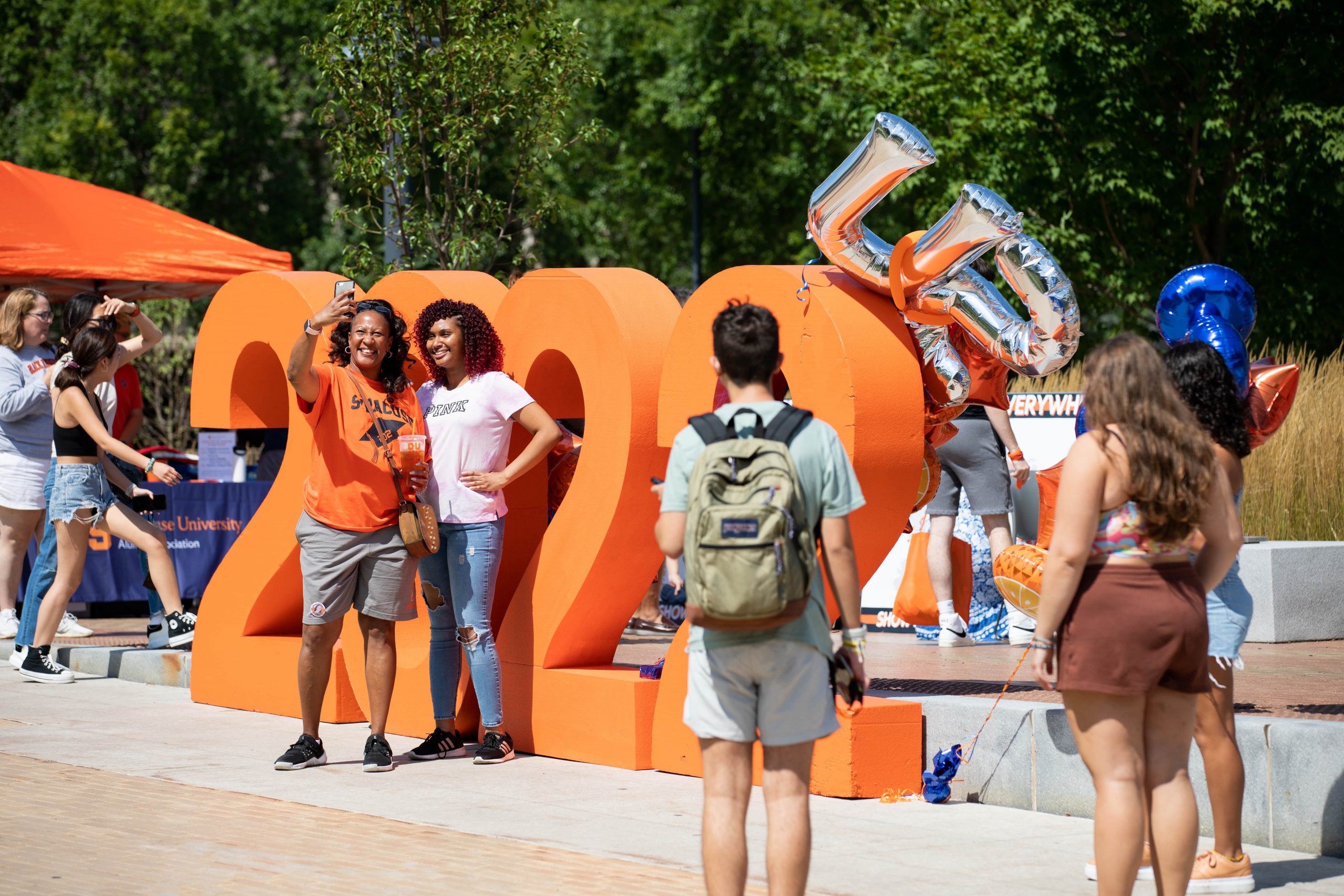 two people take a selfie in front of giant orange Block letters that say "2022" during Syracuse Welcome