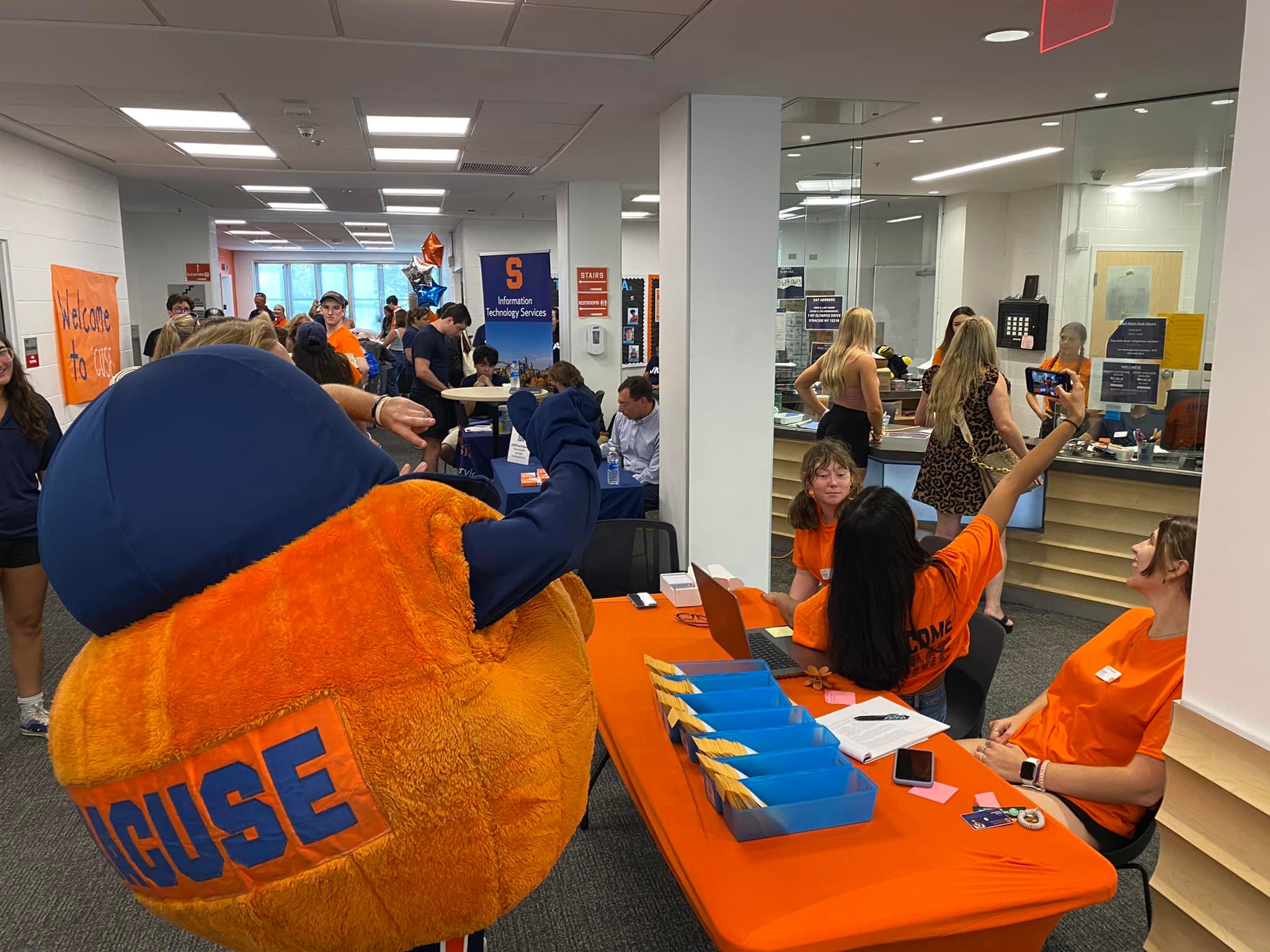 Otto takes a selfie with student volunteers at a residence hall check-in table during Syracuse Welcome