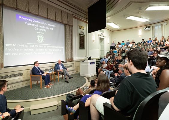 Surrounded by a crowd of participants, political science professor Chris Faricy and men's basketball coach Jim Boeheim speak to one another during a panel discussion at Maxwell titled "Renewing Democratic Community: Basketball, Leadership and Citizenship"