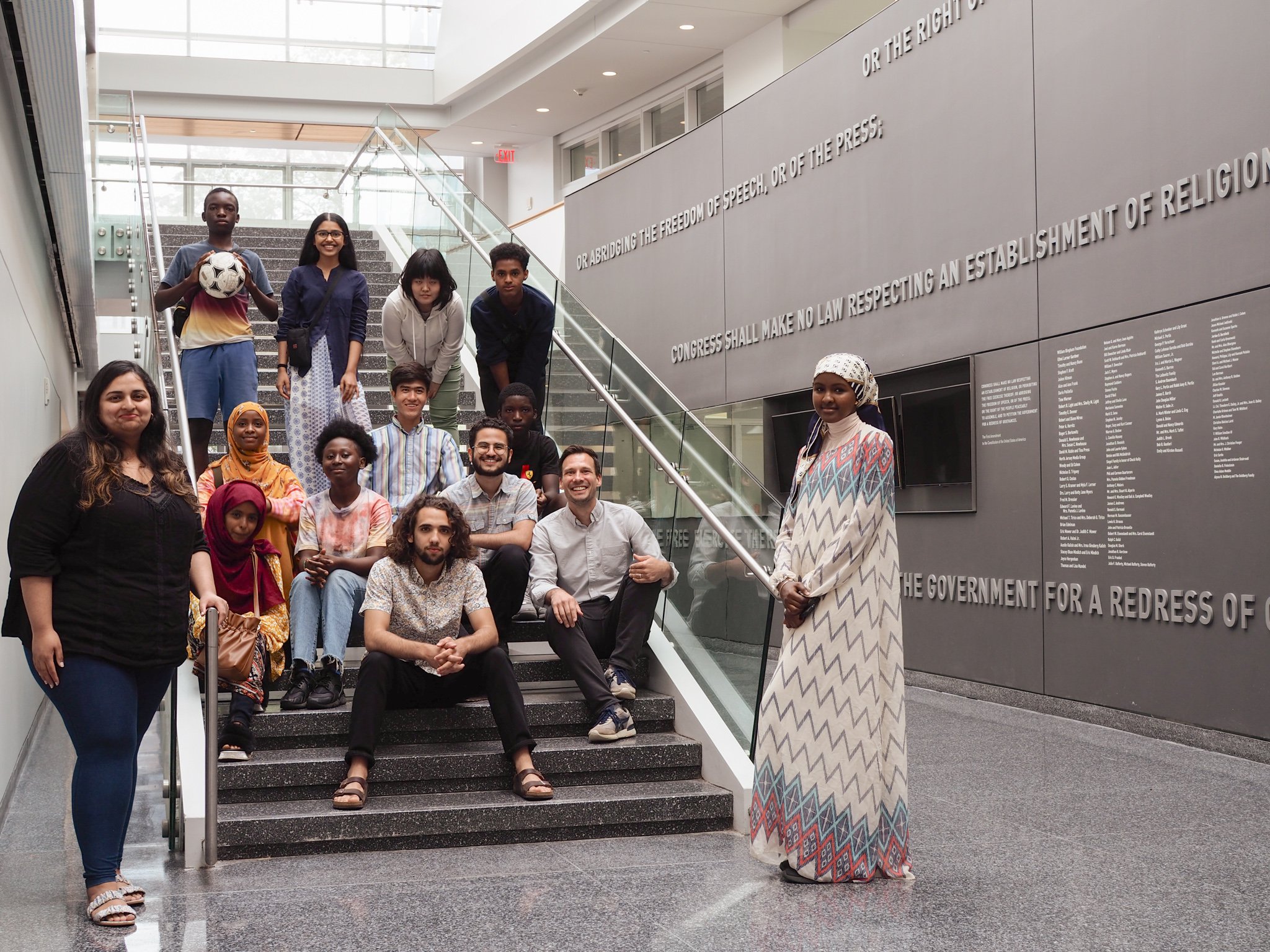 2022 Syracuse Narratio Fellowship cohort gathers together on the stairs in the Newhouse School