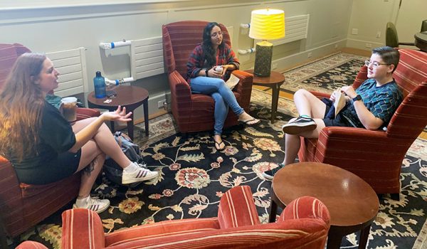 three students sit together in the Noble Room in Hendricks Chapel, talking and enjoying coffee