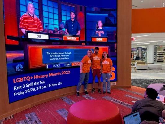 Sanjeev Uppaluri ’24, Zoë McCreary ’23, Emma Lambiaso ’24 pose in front of a screen in Schine showing their Oct. 7 "College Bowl" appearance on NBC