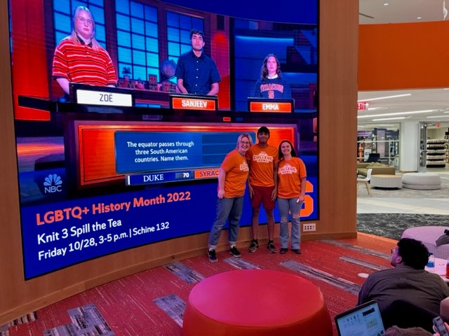 Sanjeev Uppaluri ’24, Zoë McCreary ’23, Emma Lambiaso ’24 pose in front of a screen in Schine showing their Oct. 7 "College Bowl" appearance on NBC