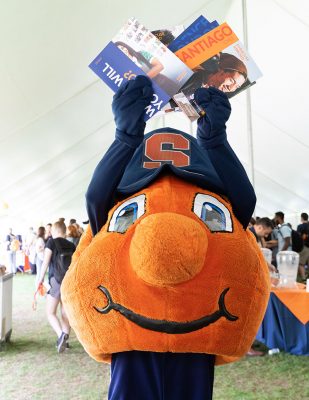 Mascot Otto the Orange holding Syracuse Abroad literature over his head