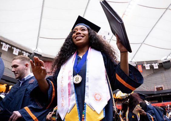 female student holding up diploma during Commencement ceremonies