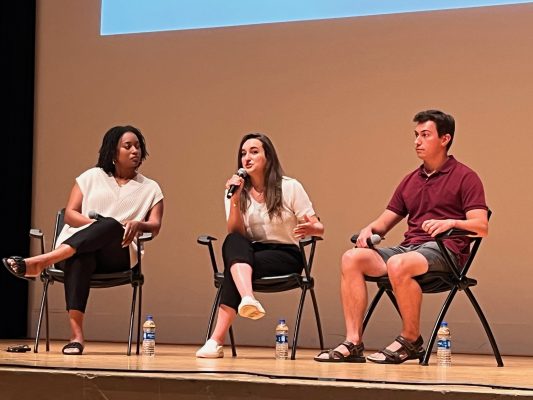 three students on stage in a panel discussion